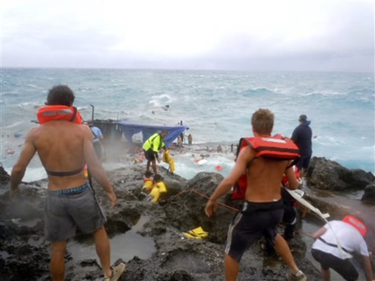 People clamber on the rocky shore on Christmas Island during a rescue attempt as a boat breaks up in the background Wednesday, Dec. 15, 2010. A wooden boat packed with dozens of asylum seekers smashed apart on cliff-side rocks in heavy seas off an Australian island Wednesday, sending some to their deaths in churning whitewater. (AP Photo/ABC) AUSTRALIA OUT